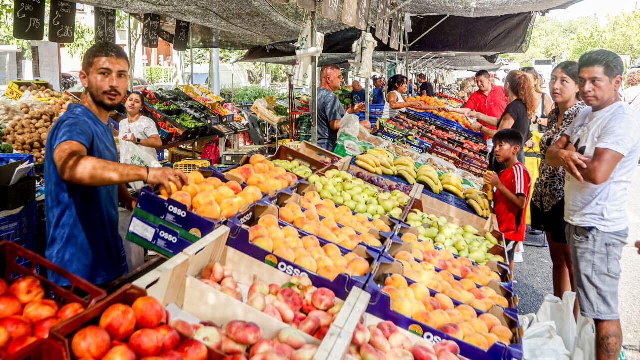 A marketstall holder with fruit and vegetables.
