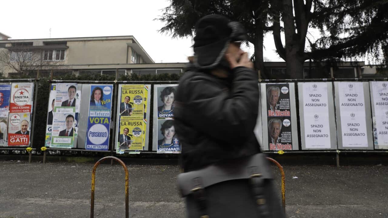 A man walks past electoral posters after leaving a polling station in Milan.