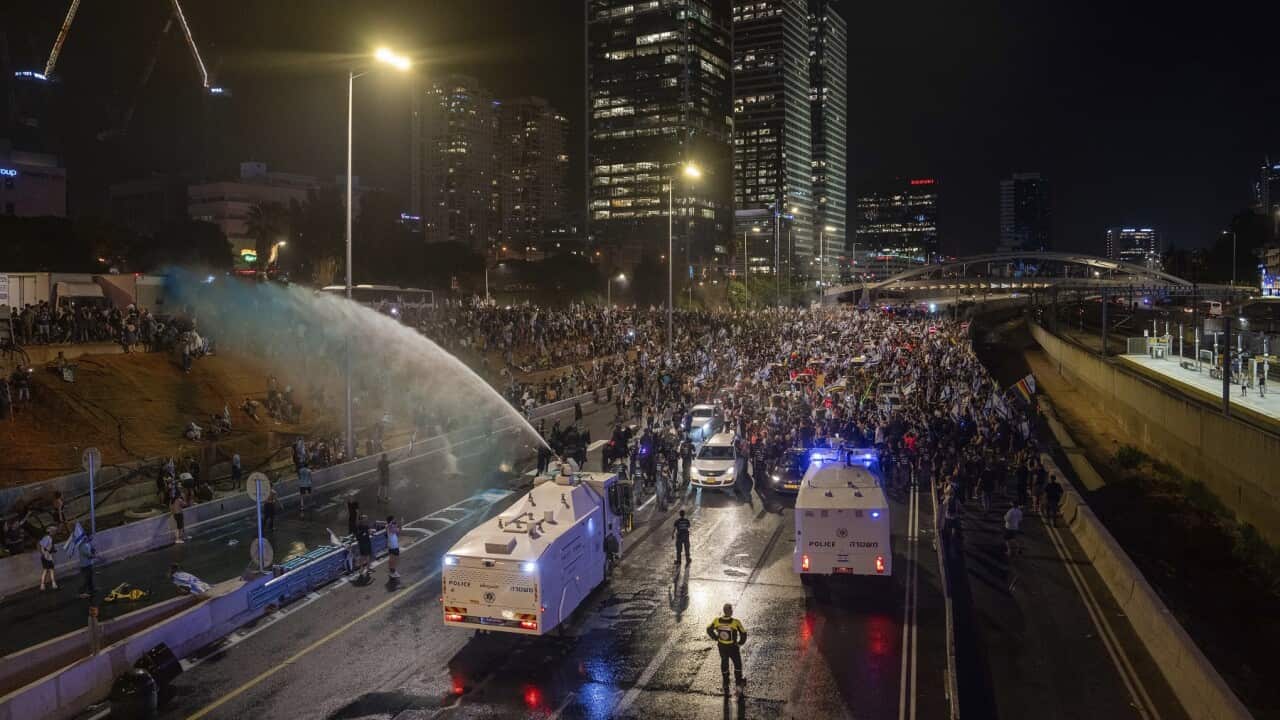 Riot police try to clear demonstrators with a water cannon during a protest in Tel Aviv