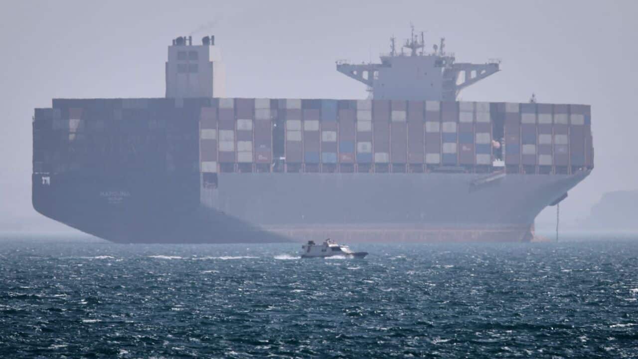 A container ship sits at anchor as a small motorboat passes in the foreground in the Strait of Hormuz off Bandar Abbas, Iran, Saturday, May 2, 2026. (Amirhosein Khorgooi-ISNA via AP).jpg