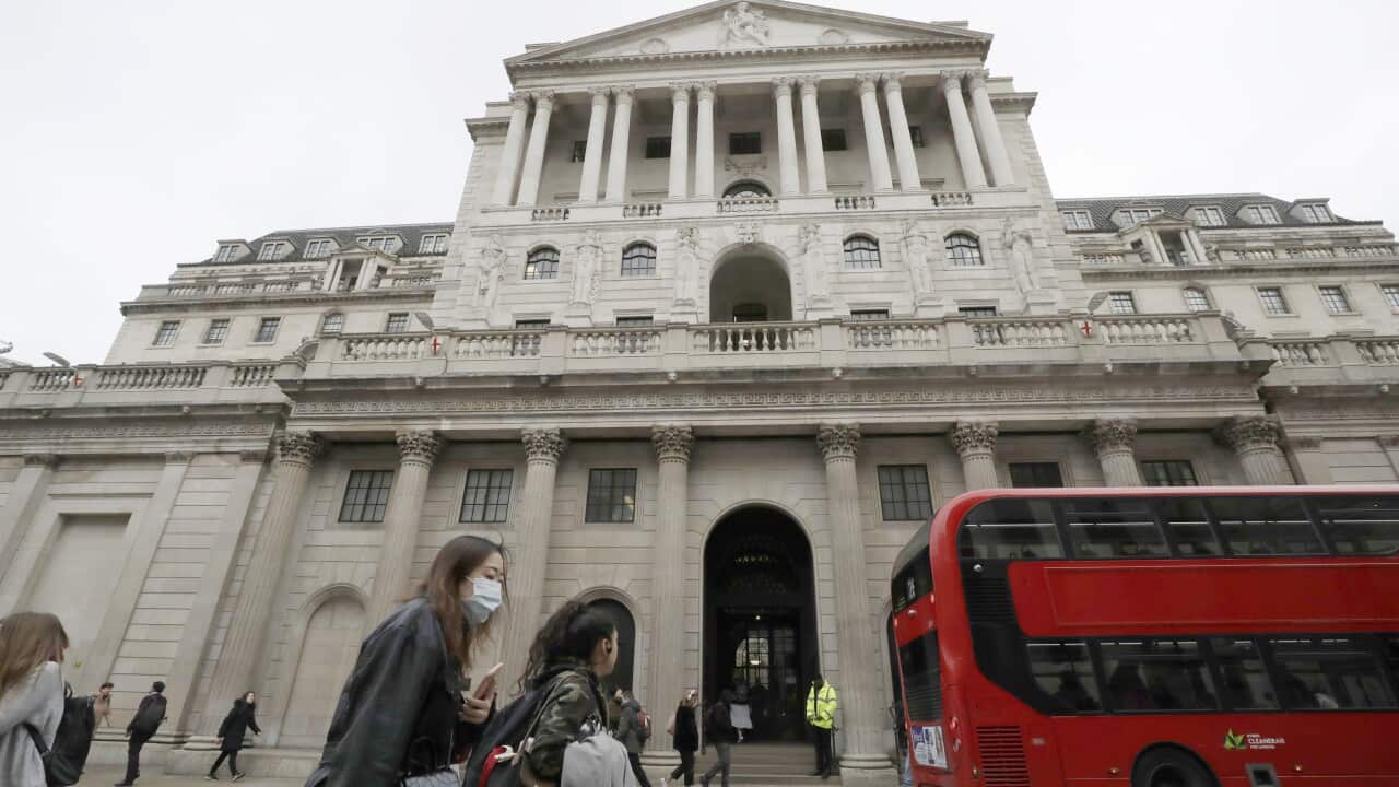 Pedestrians wearing face masks walk past the Bank of England in London, Wednesday.