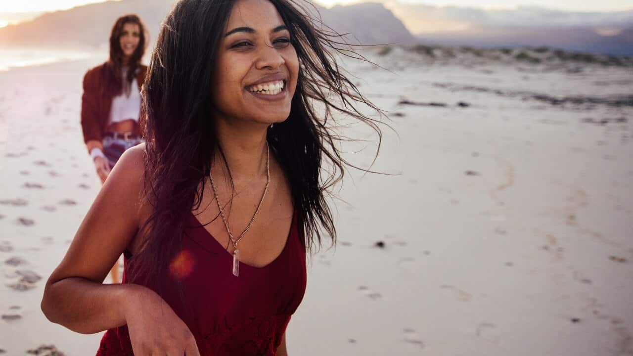 Happy multi-ethnic hipster friends walking on the beach