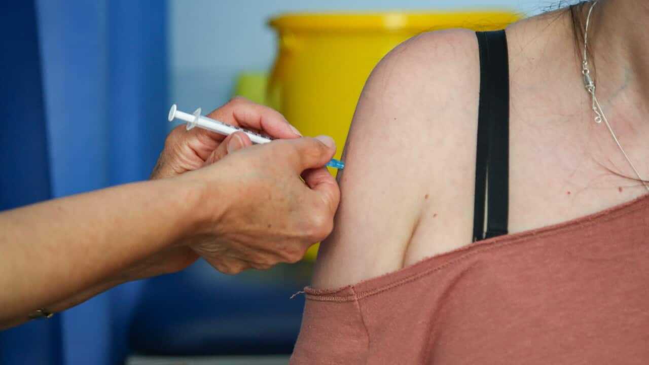 A person receives a COVID-19 vaccine injection in their upper arm from a healthcare worker.