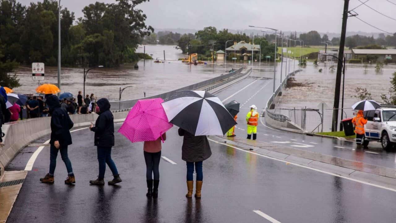 People look on as flood water rises over the New Windsor Bridge on The Hawkesbury River in Windsor on 21 March in Sydney, Australia.