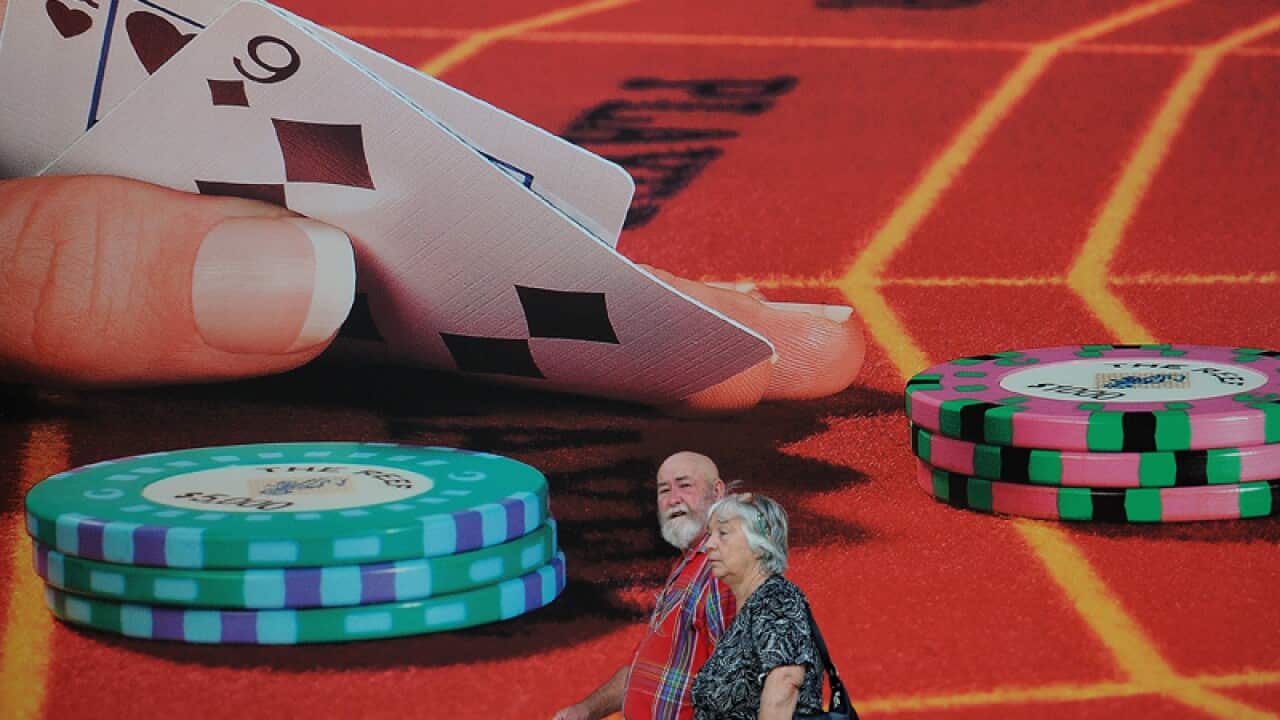 A couple walk past advertising outside the casino in Cairns