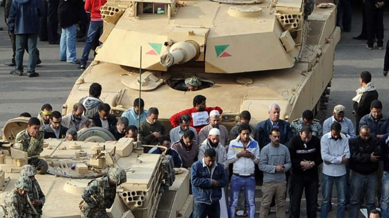 Egyptian demonstartors pray in front of an Abrams tank in Tahrir Square, in Cairo.
