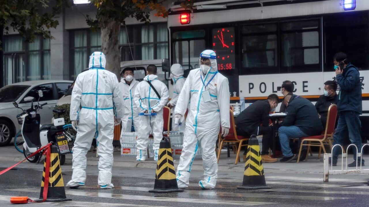 Epidemic prevention and control staff wearing protective suits guard an entrance to a residential neighbourhood in Beijing.
