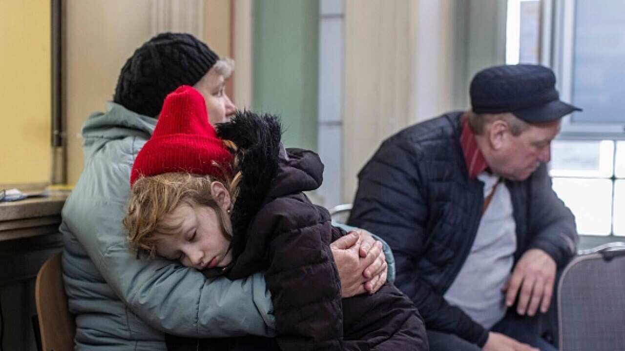 A little girl from Lviv named Katia is seen sleeping in her grandmother Luba's arms at the railway station in Przemysl, southeastern Poland, on 3 April 2022.