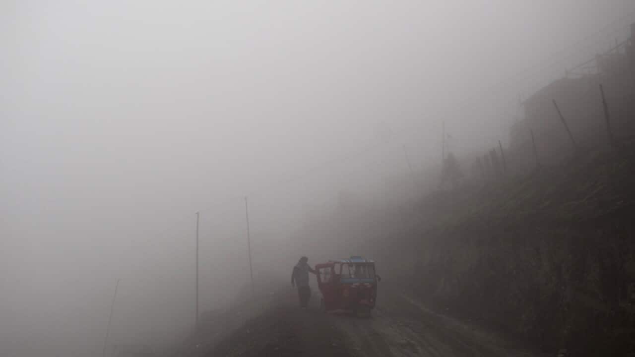 A man approaches his motorcycle taxi during a foggy morning in Lima