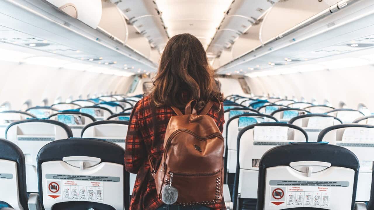 A woman walks up the aisle of a plane