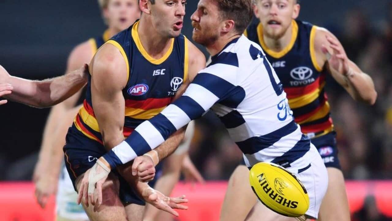 Taylor Walker of the Crows and Zach Tuohy of the Cats in action.