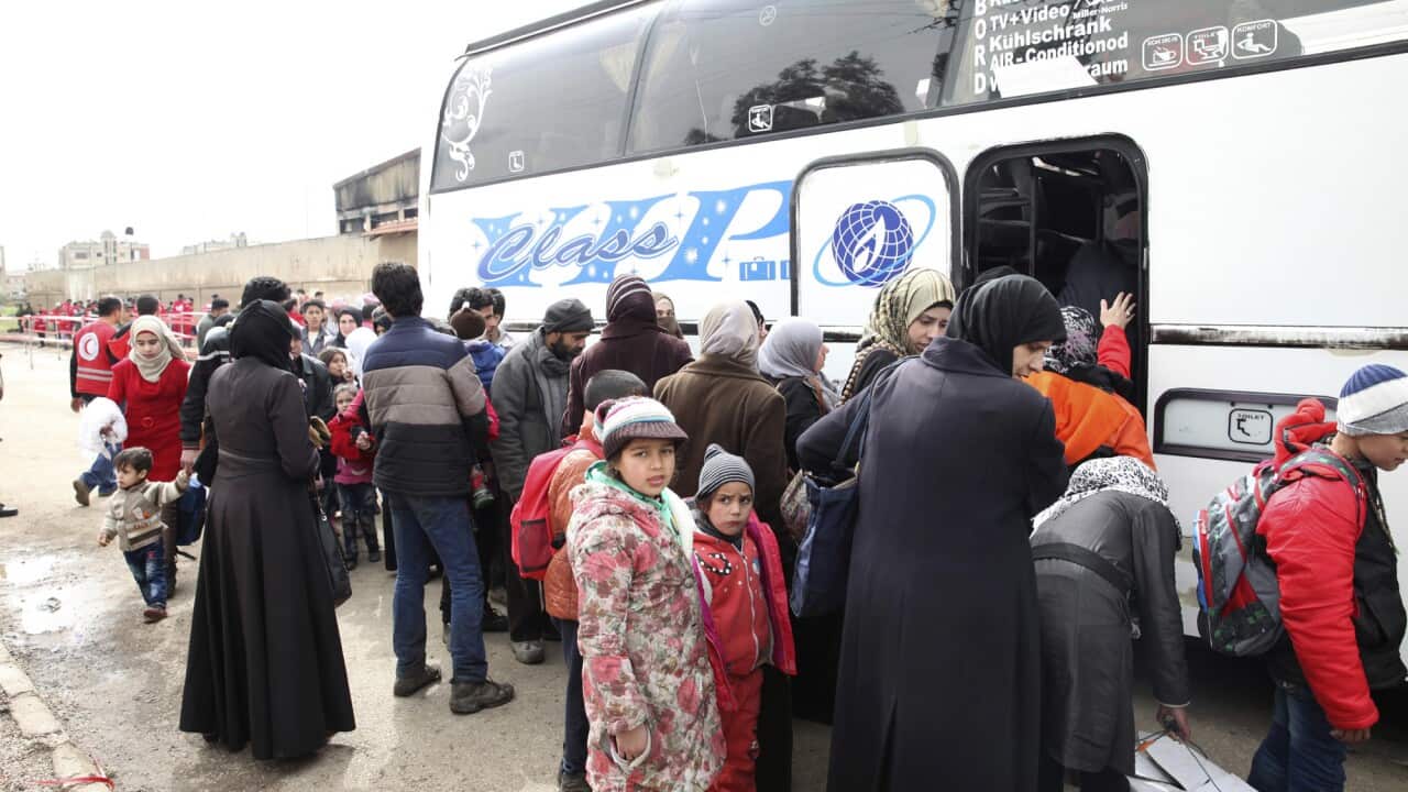 Women and children board buses to leave the al-Waer neighborhood bound for a town on the Turkish border, in Homs, Syria