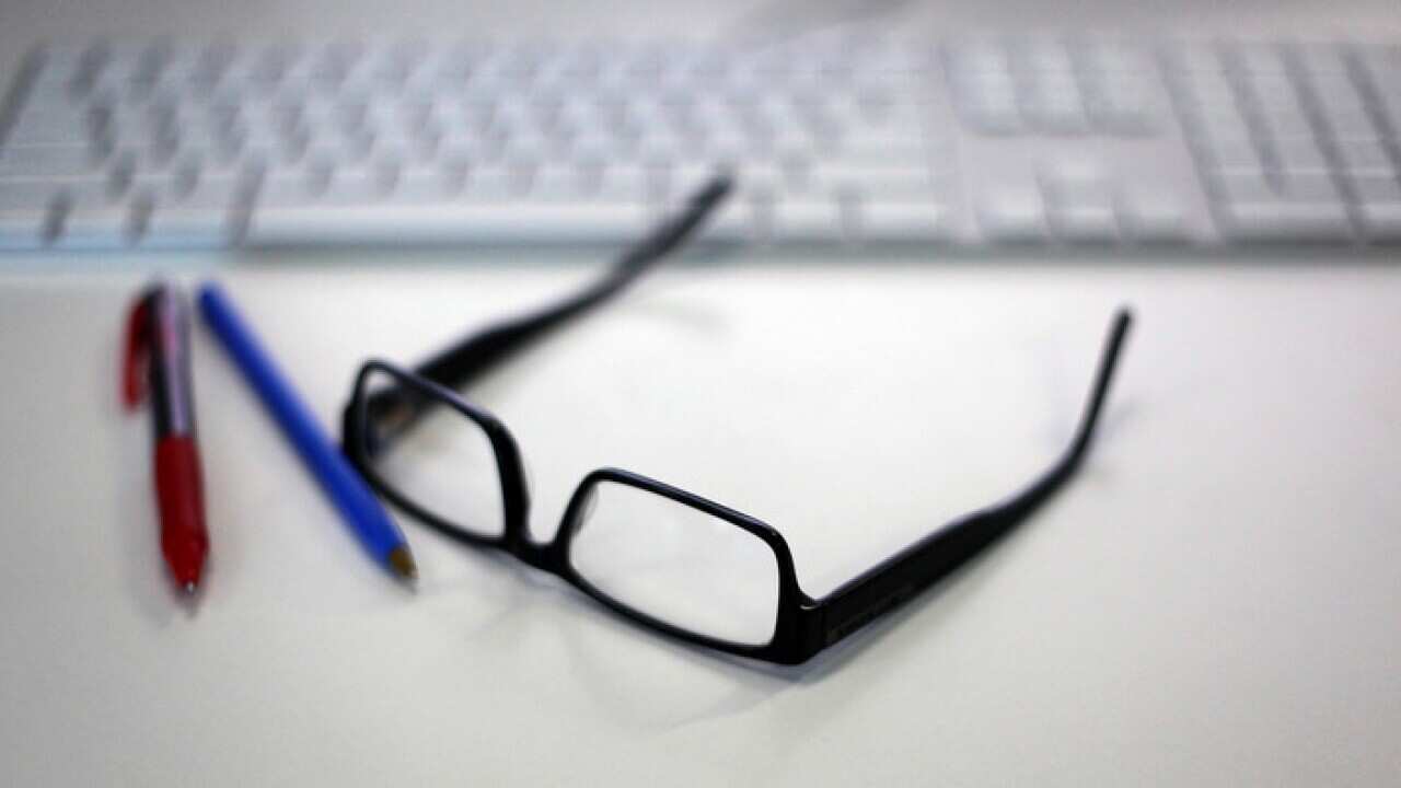 Reading glasses is featured alongside a Macintosh keyboard and office supplies in a stock image in Sydney, Wednesday, Jan. 13, 2016. (AAP Image/Sam Mooy) NO ARCHIVING