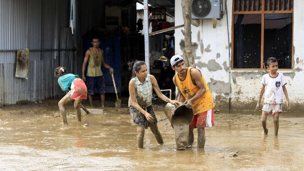 People clear away mud after the 2021 floods.