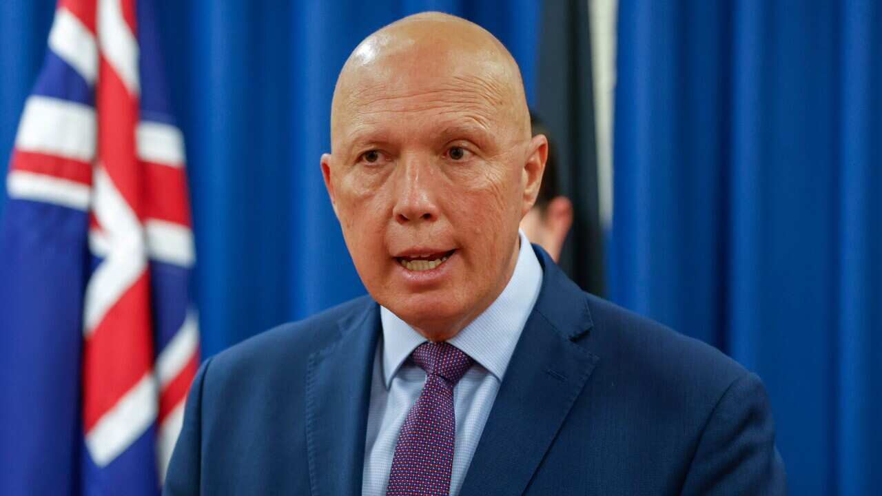 Peter Dutton standing in front of Australian flag speaking