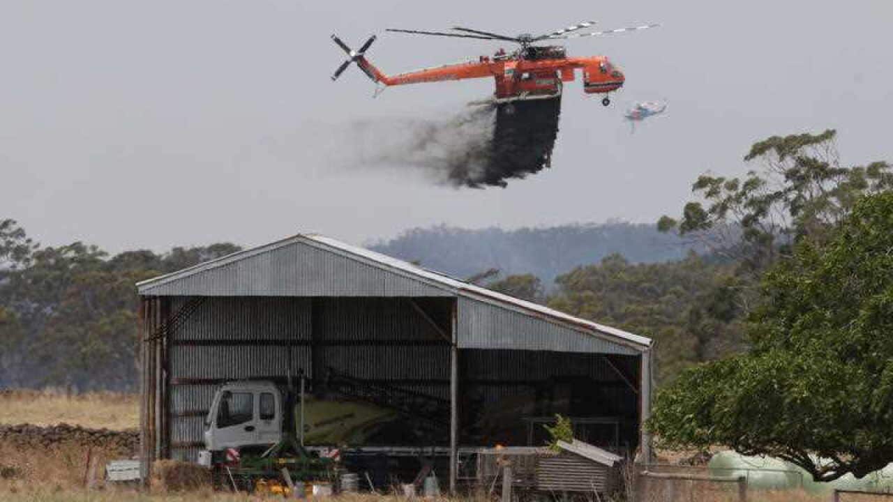 The sky crane helicopter works to hold back a bushfire from the hamlet of Claredon, South of Ballarat in Victoria