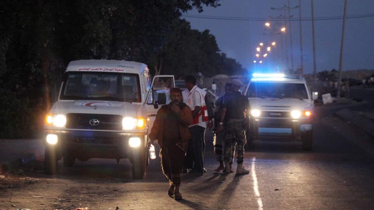 Yemeni officials gather at the site of a bomb blast Aden