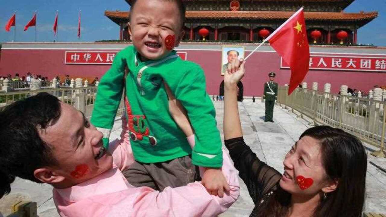 A Chinese family of three poses for a photo in front of the Tian'anmen Rostrum in Beijing