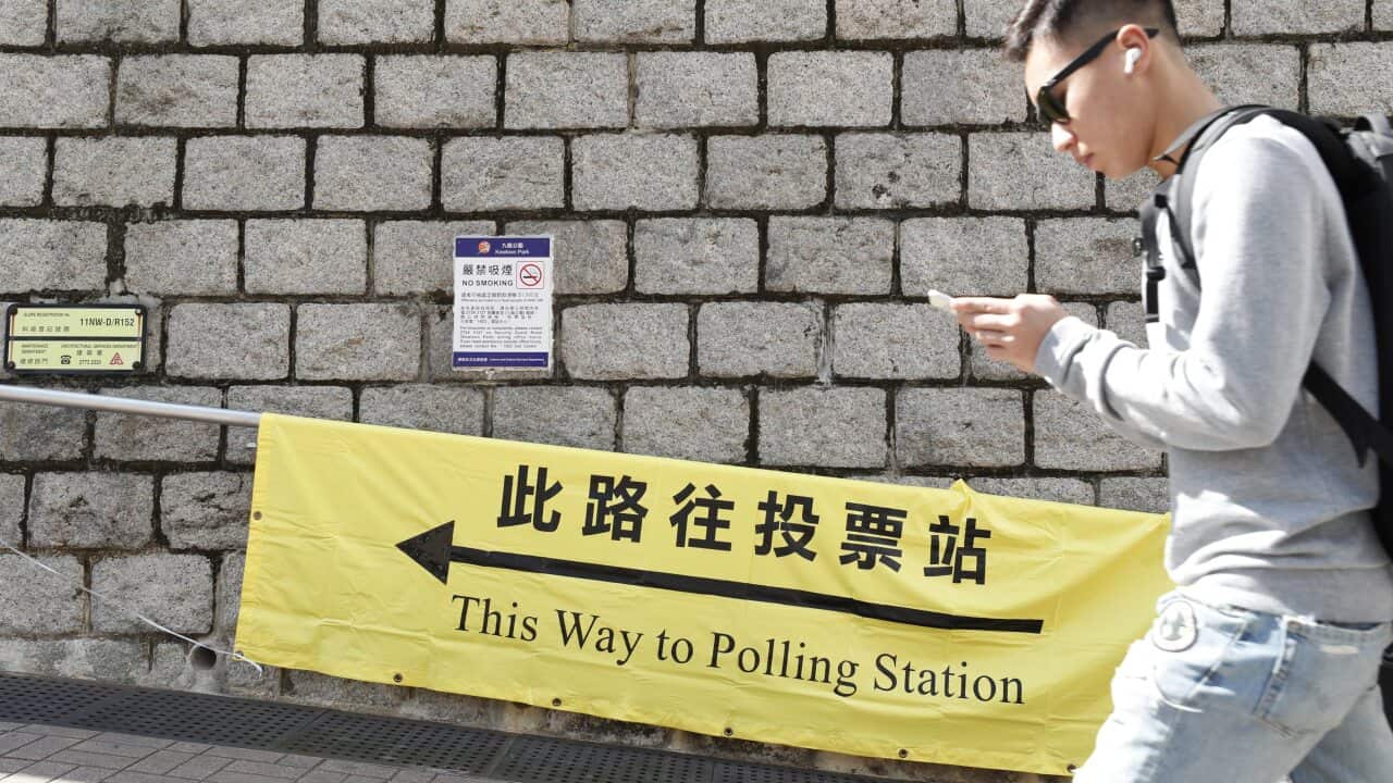 A person walks past a banner showing the way to a polling station for the 2019 District Council Ordinary Election in Hong Kong.