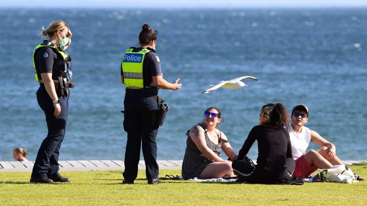 Police speak to people enjoying the unusually warm spring weather at St Kilda Beach in Melbourne on September 2, 2021, as the city remains in lockdown.
