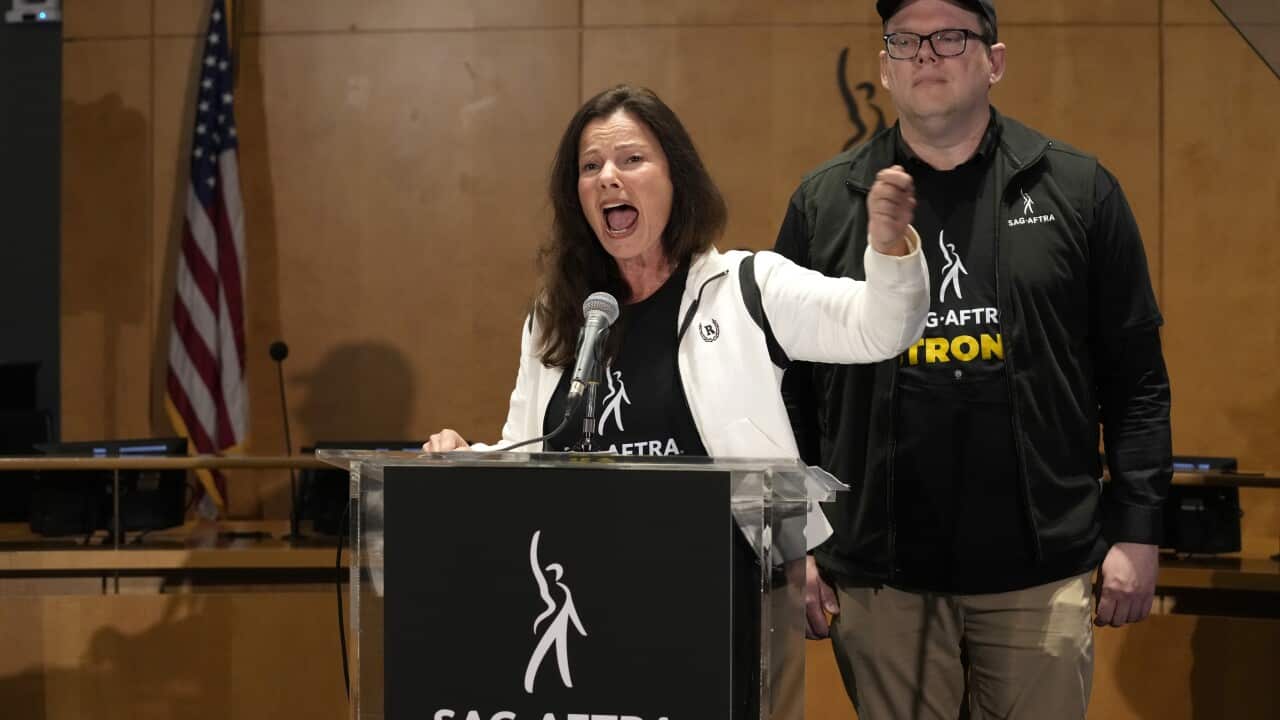 Actor Fran Drescher speaking behind a lectern, wearing a black t-shirt with the logo of SAG-AFTRA.