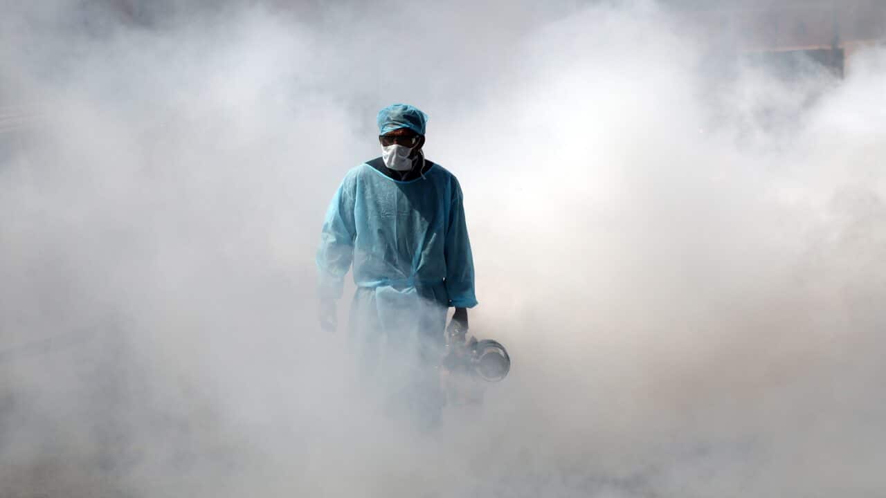 A Jammu Municipal Corporation health worker sprays disinfectant in a deserted market street in Jammu, India