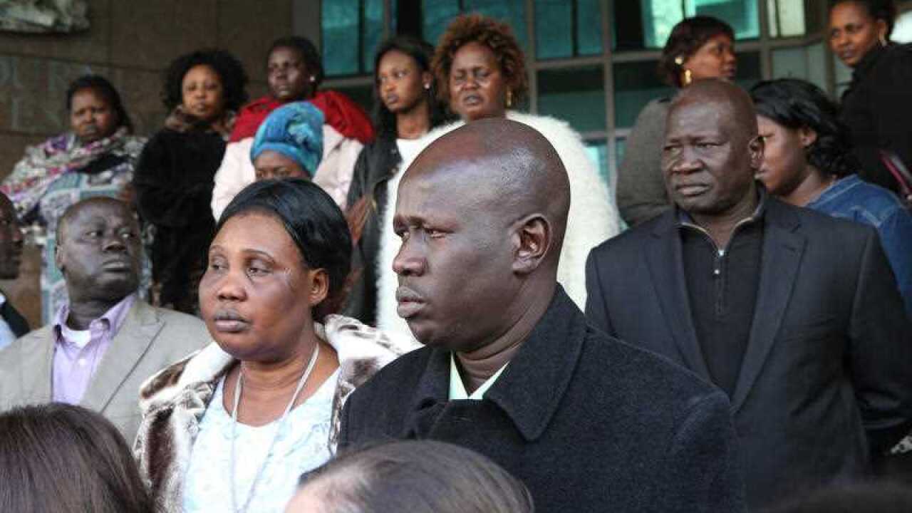 Joseph Tito Manyang (centre), the father of the three children killed in a Wyndam Vale lake, leaves the Melbourne Magistrate Court.