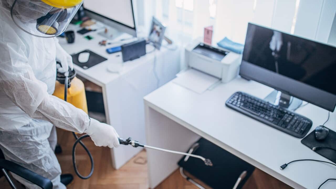 A man in protective suit disinfecting office work space