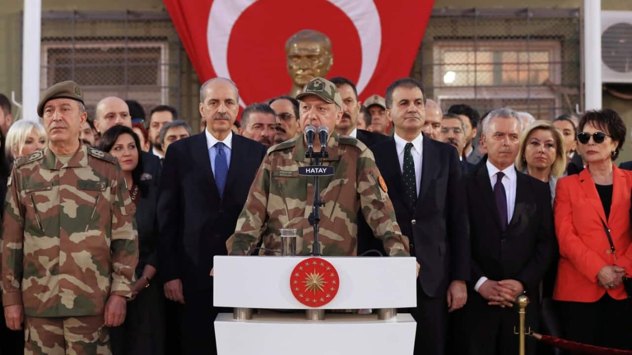 Turkey's President Recep Tayyip Erdogan, in full military combat uniform, center, flanked by army generals, his ministers and Turkish singers