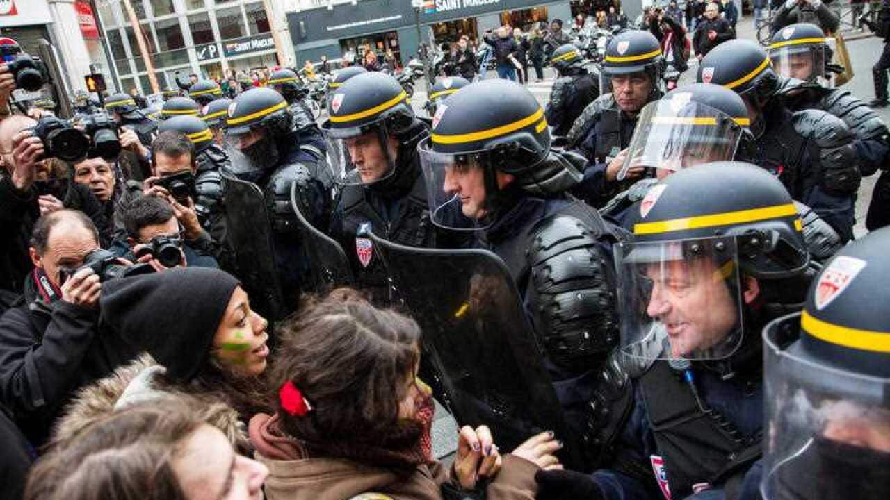 Protestors gesture in front of riot police during clashes following a rally against global warming on November 29, 2015 in Paris, a day ahead of the start of the UN conference on climate change (COP21). (AAP)