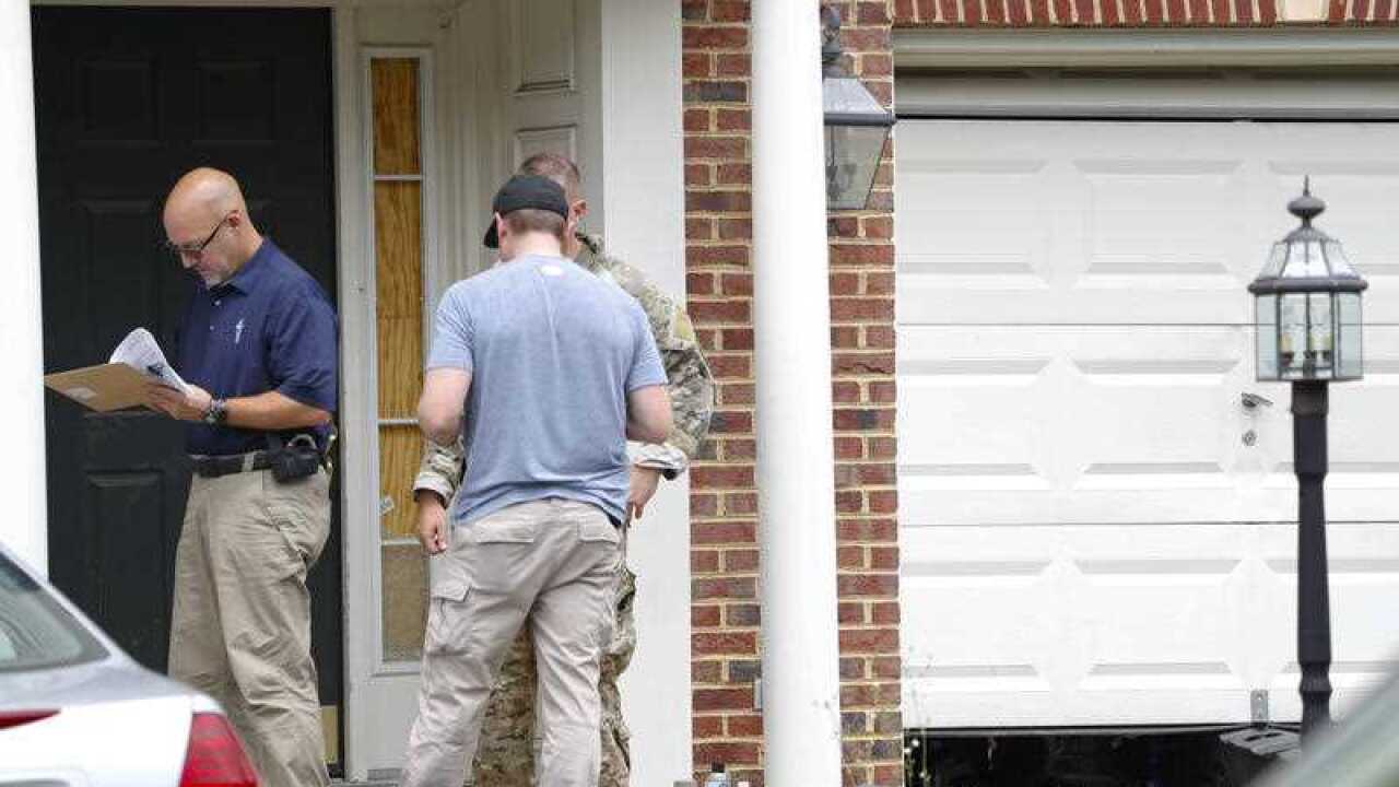 Law enforcement officers stand outside the home of Nicholas Young, a Washington Metro Transit Officer, Wednesday, Aug. 3, 2016, in Fairfax, Virginia.