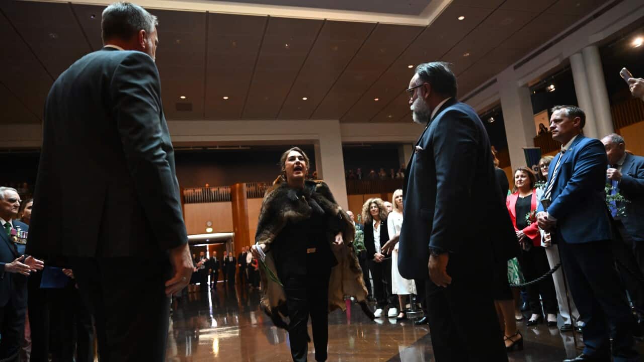 A woman in black attire is walking while shouting.