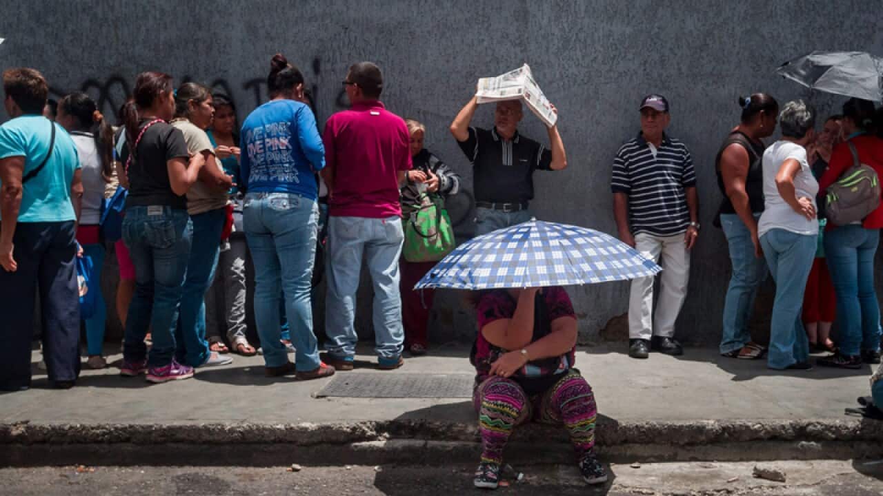 People line up to get food at a distribution point in Caracas