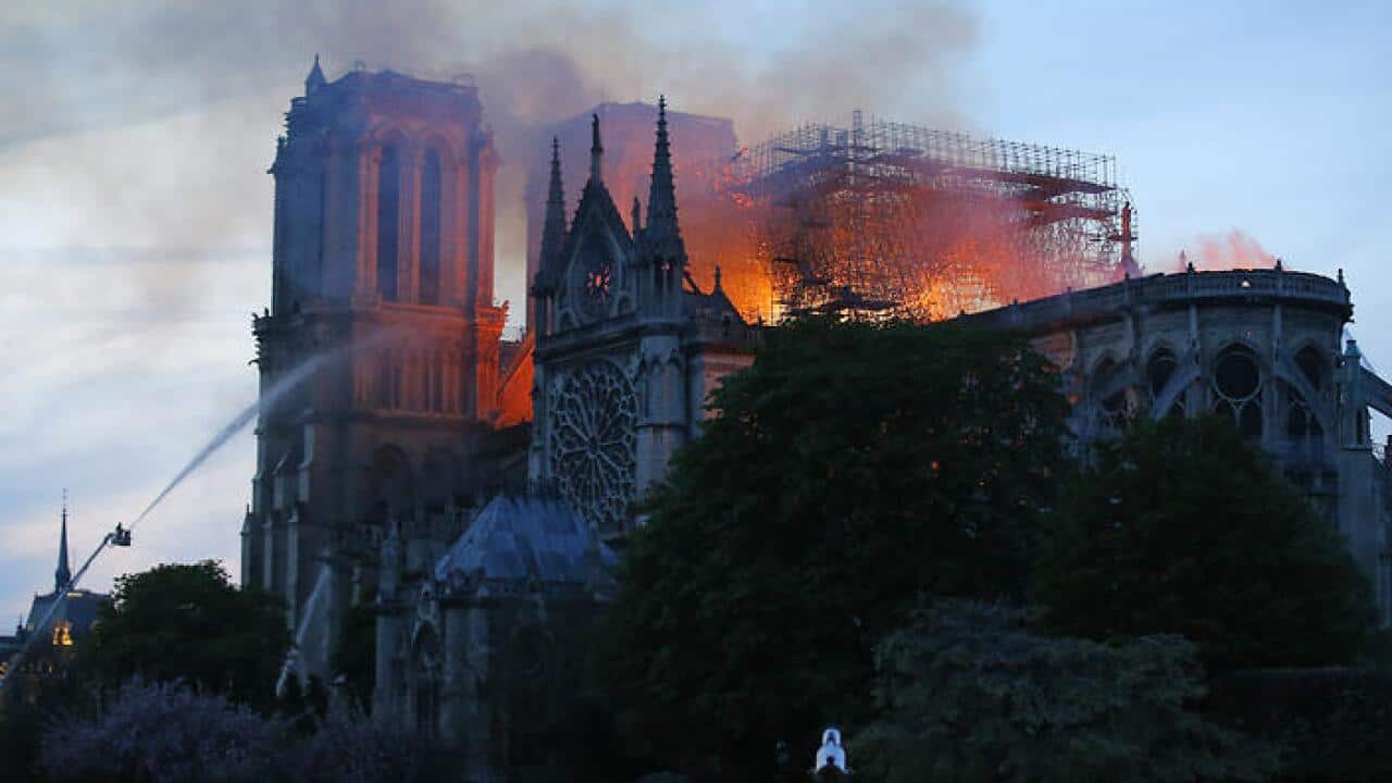 Massive plumes of yellow brown smoke is filling the air above Notre Dame Cathedral and ash is falling on tourists and others around the island that marks the center of Paris.