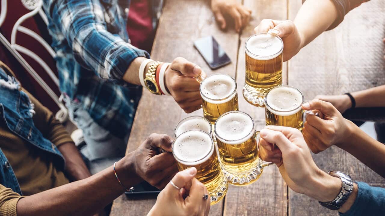 Group of people enjoying and toasting a beer in brewery pub - Friendship concept with young people having fun together