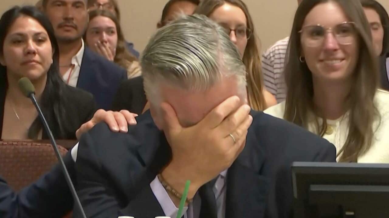 Actor Alec Baldwin covering his face while weeping.