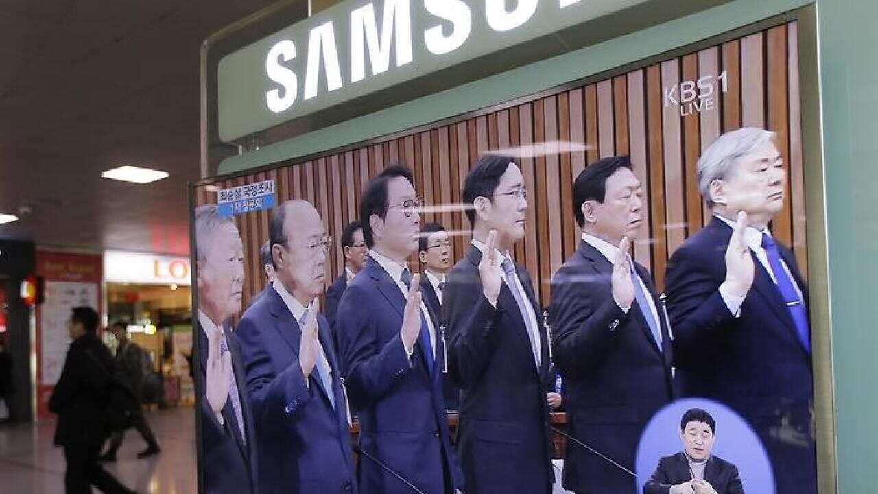 A TV screen shows the leaders of the top Korean conglomerates called in Parliamentary hearing