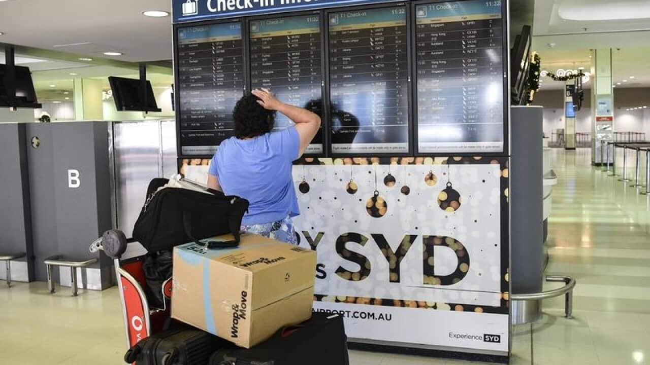 A traveller examines a check-in board at an airport.