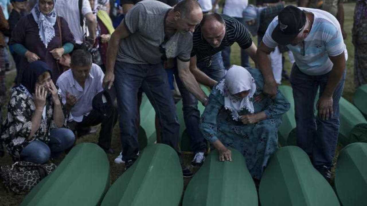 A family grieves next to coffins containing the remains of victims of the Srebrenica massacre