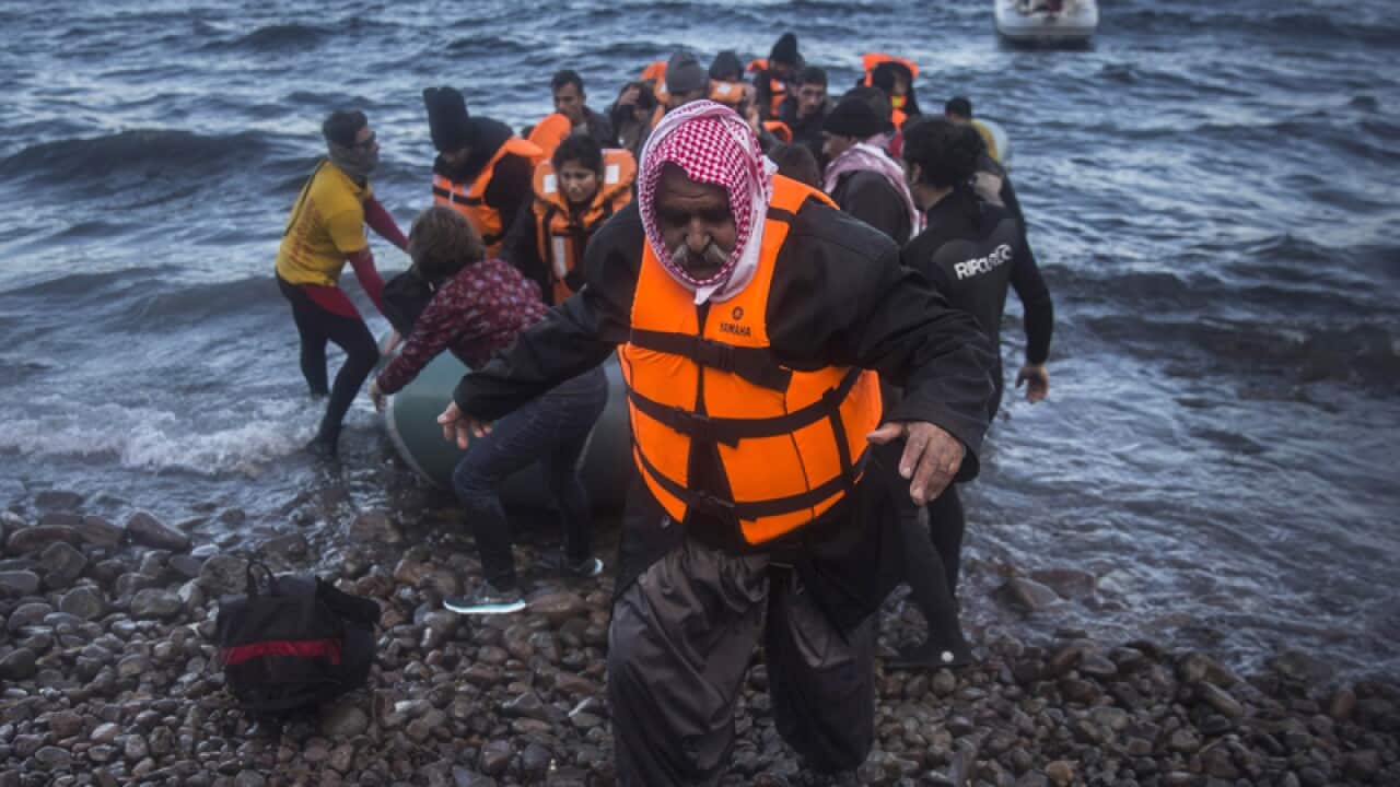 An Iraqi man disembarks from a dinghy on a beach in Greece