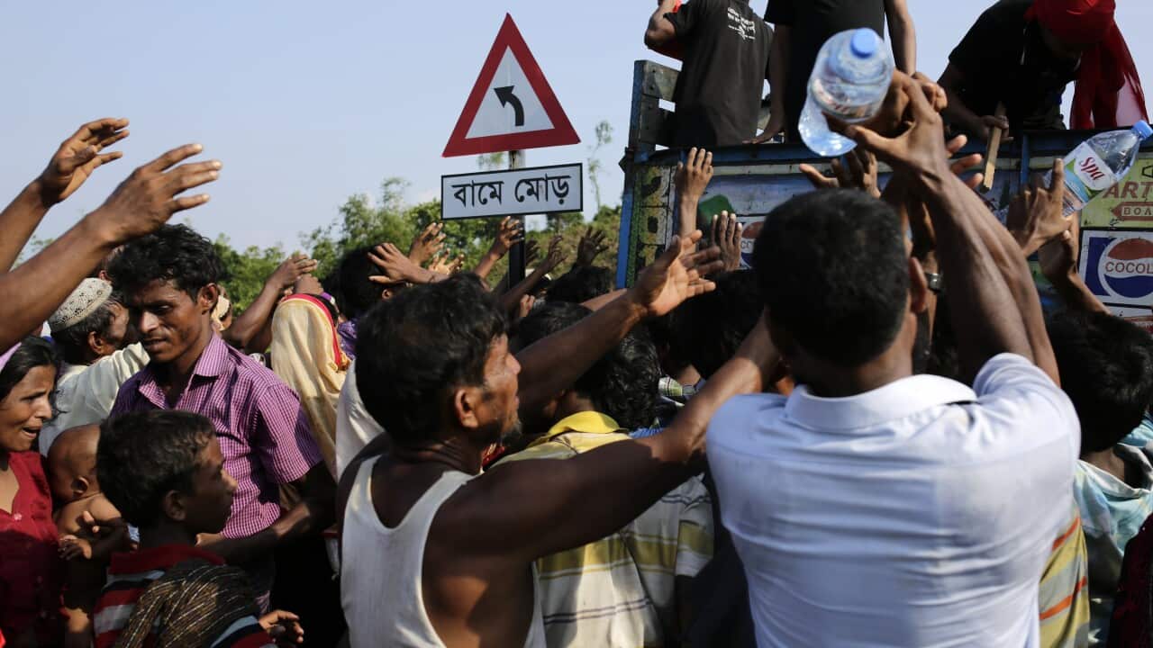 Rohingya refugees raise their hands as they collect relief at Palongkhali Bazar in Bangladesh.