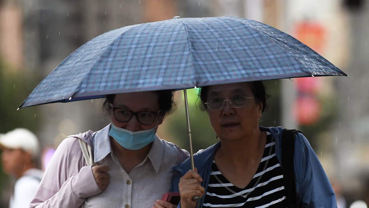 Two women walking outside under an umbrella