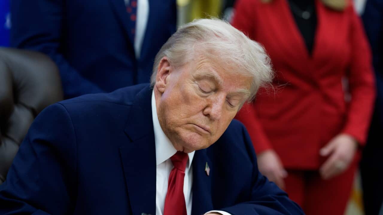 US president Donald Trump signing a piece of paper
