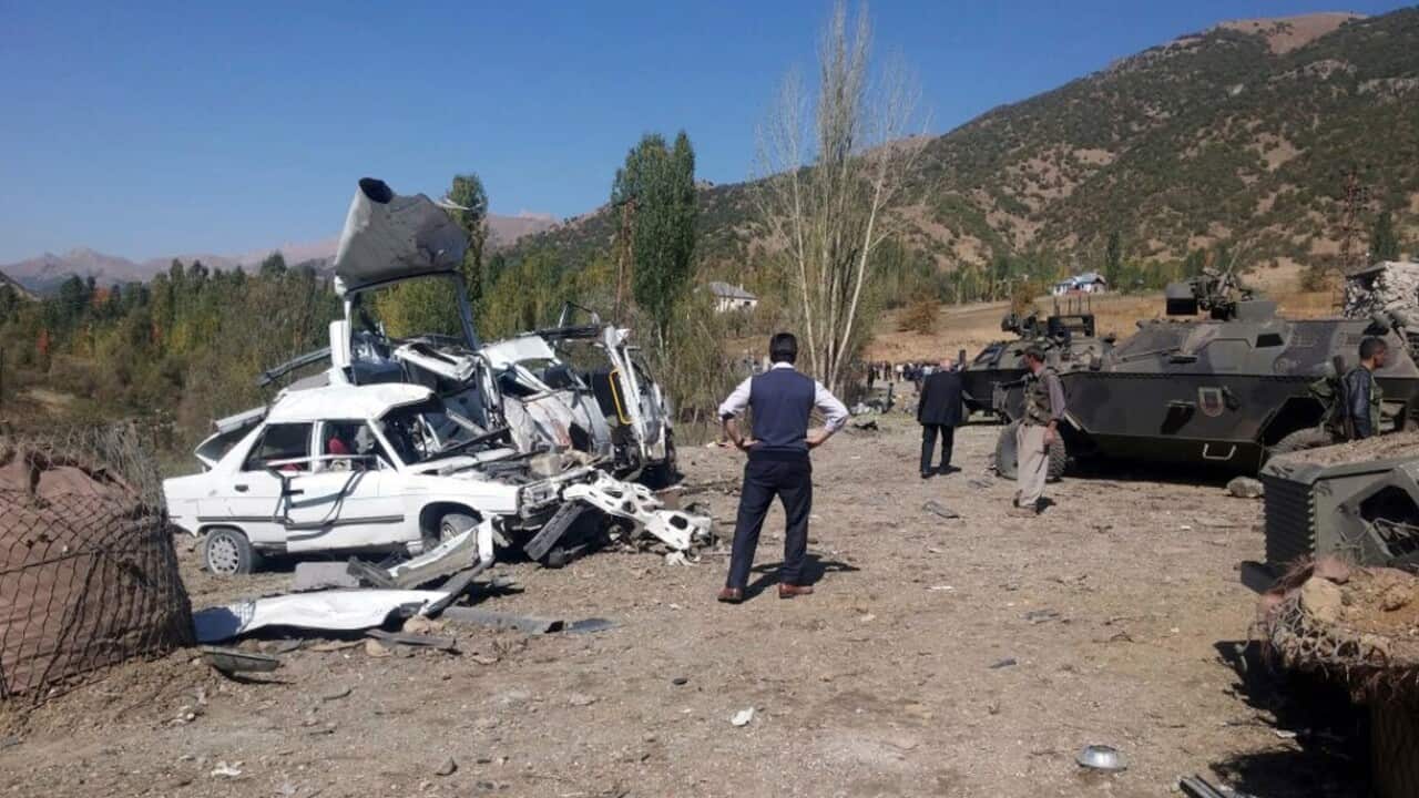 Soldiers, security members and people work at the scene of a car bomb attack in Semdinli, near the border with Iraq, Turkey, Sunday, Oct. 9,