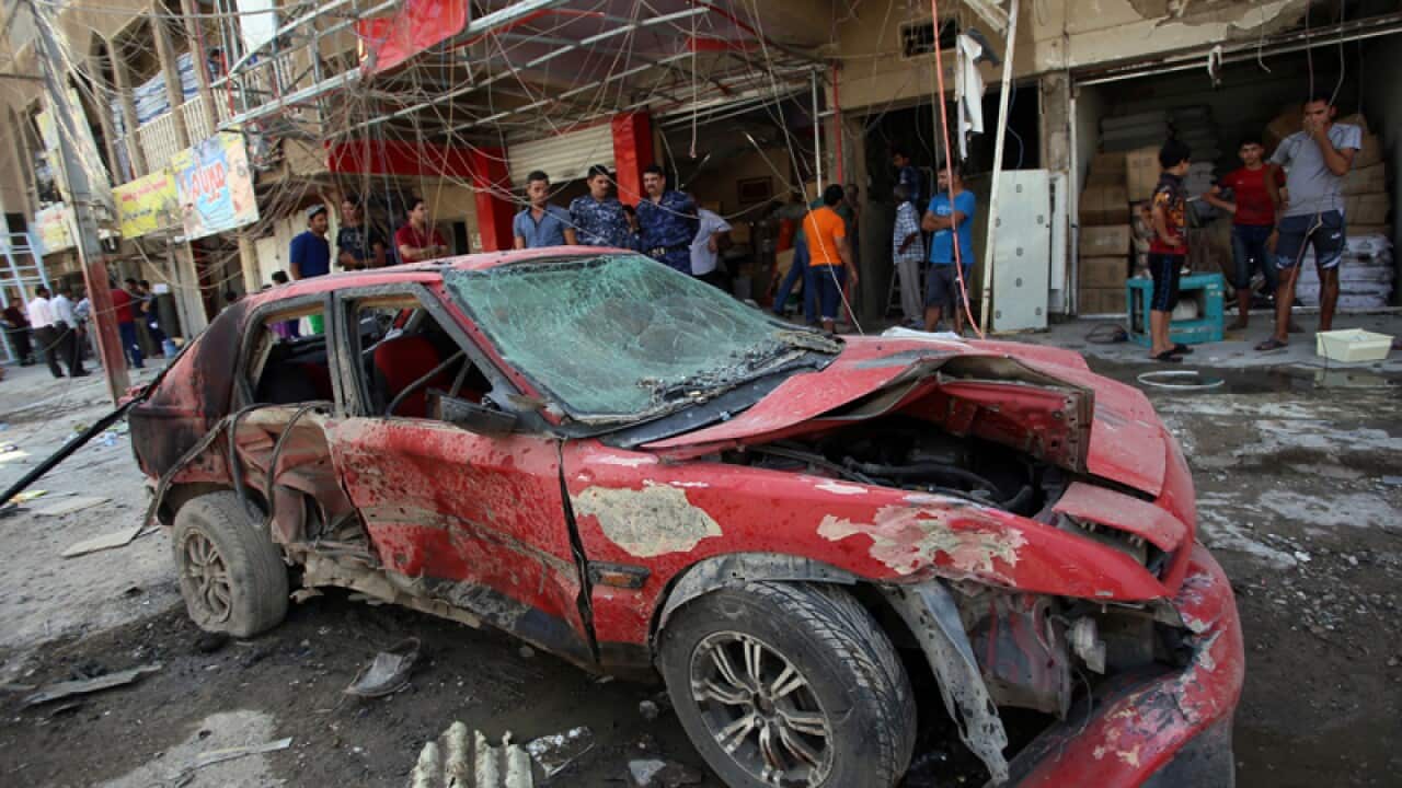 Iraqi civilians check the site of an explosion in Baghdad