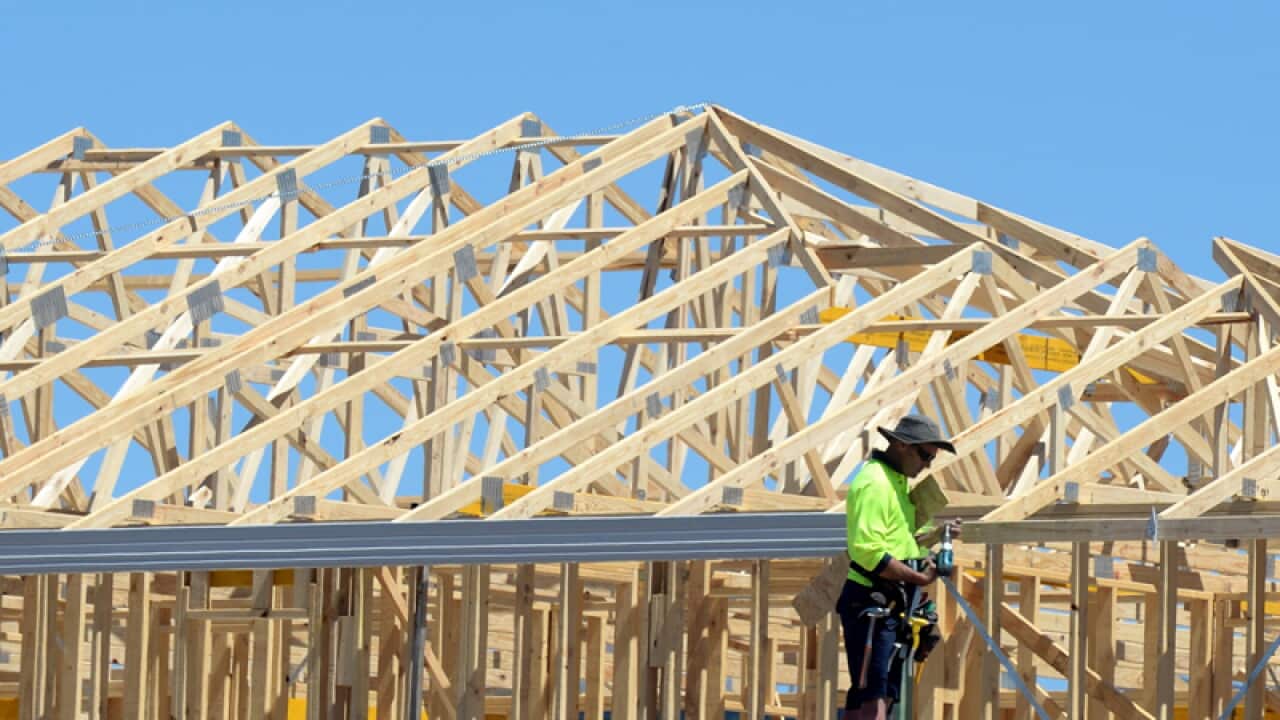 A carpenter is seen working on a home under construction