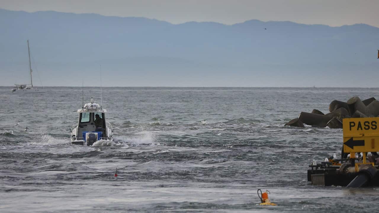 A boat slices through a tsunami surge at the mouth of the Santa Cruz Small Craft Harbor and heading out to the relative safety of the open water.