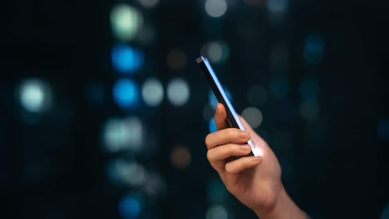 Close up shot of female hand using smartphone at night, against illuminated and defocused bokeh in background. Lifestyle and technology