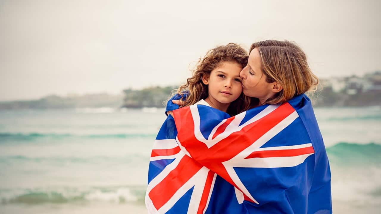 Mother kissing daughter and they are covered by Australian flag