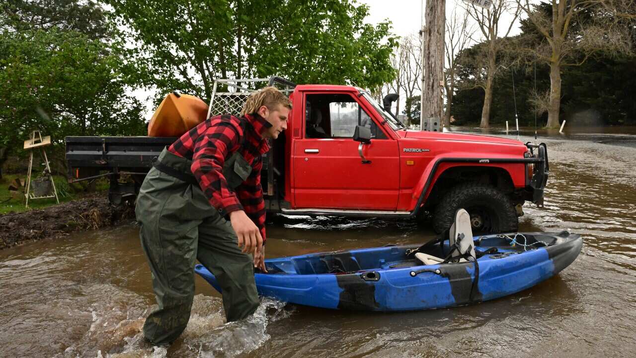 A person pushes a kayak through flood water.